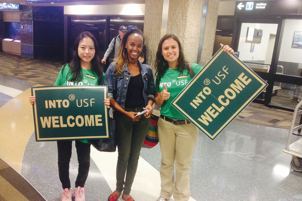 A new student is greeted by INTO staff holding INTO USF welcome banners at Tampa Airport