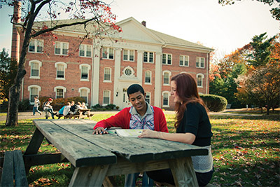 学生坐在大学大楼外的长凳上