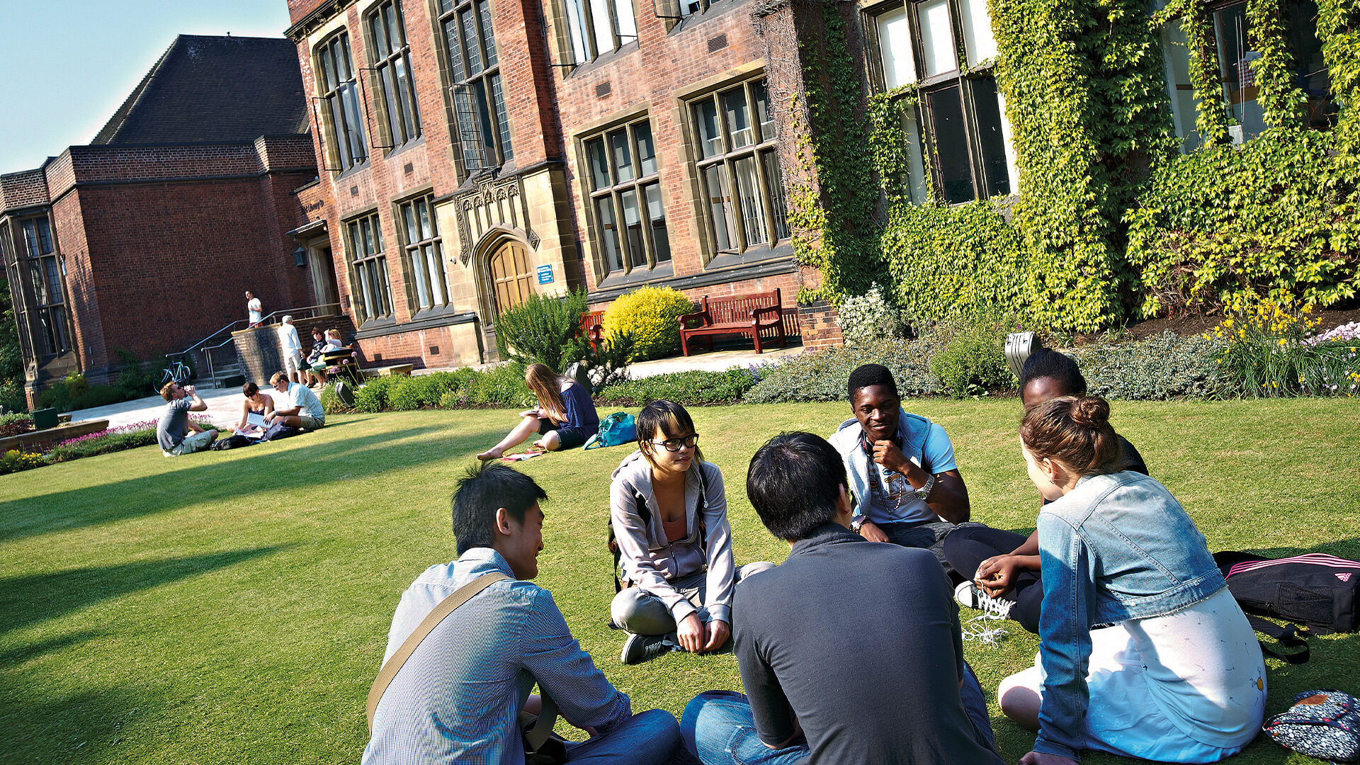 Students socialising outside on the lawn on the Newcastle University campus