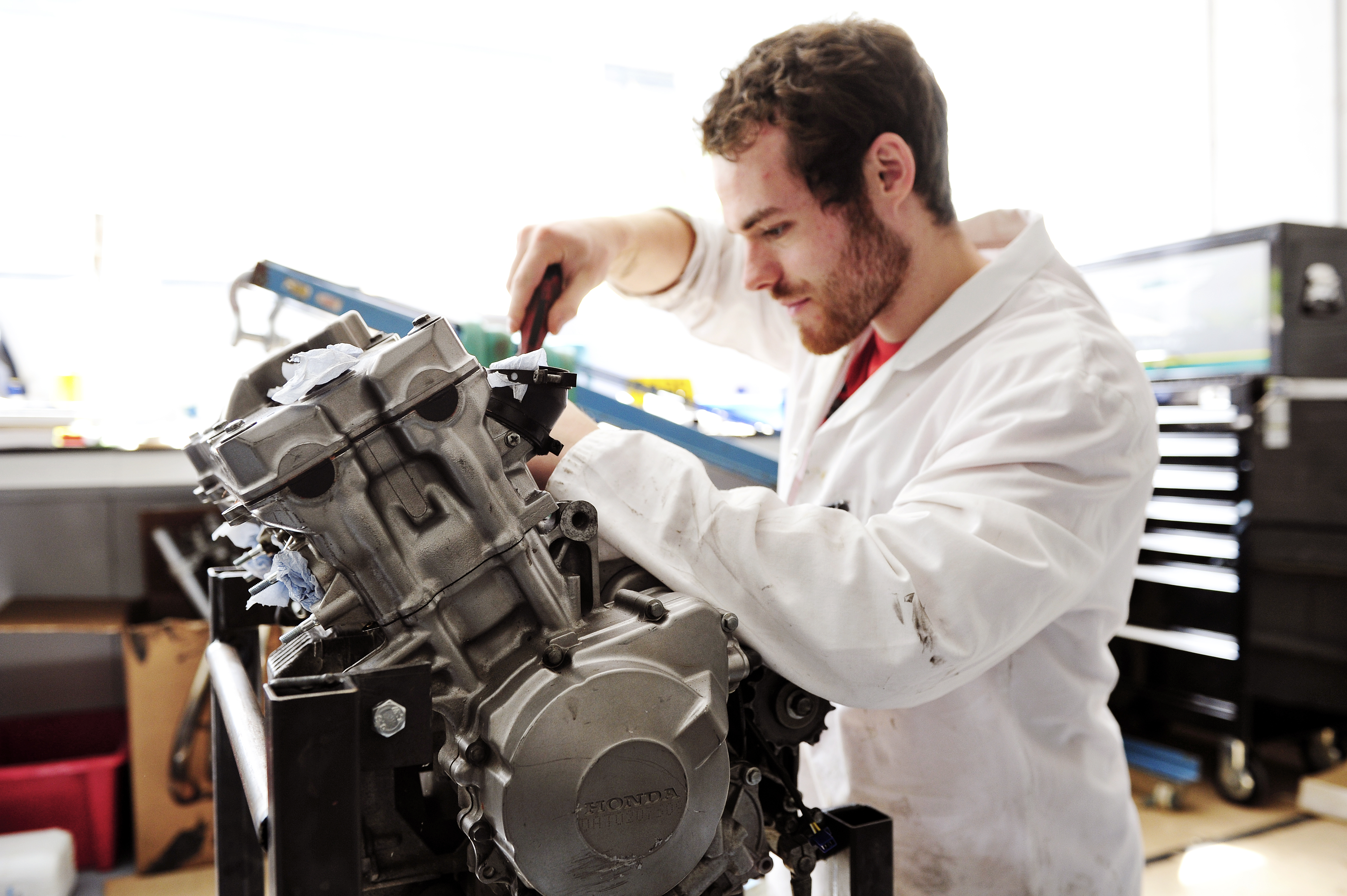 Engineering student in lab coat works on engine at University of Exeter